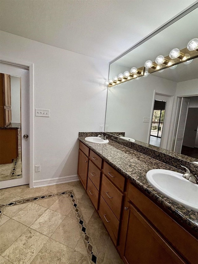 bathroom with double vanity, a sink, and baseboards