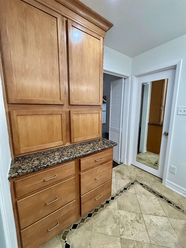 interior space featuring baseboards and dark stone counters