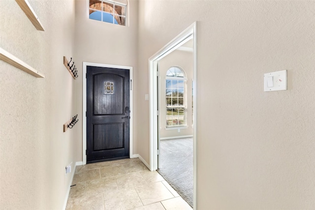 entryway featuring light tile patterned floors, baseboards, and light colored carpet