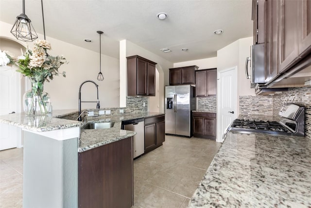 kitchen with light stone counters, a sink, dark brown cabinets, appliances with stainless steel finishes, and decorative light fixtures