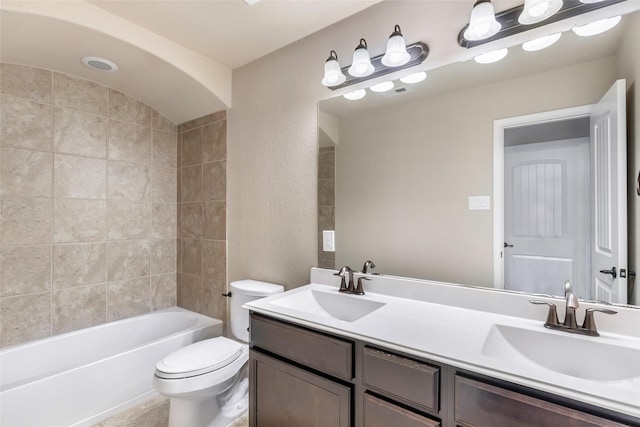 bathroom with toilet, double vanity, and a sink