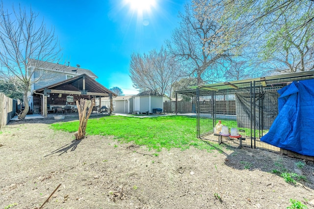 view of yard with an outbuilding, a fenced backyard, and a patio