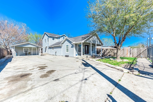 view of front of house featuring driveway, a porch, and fence