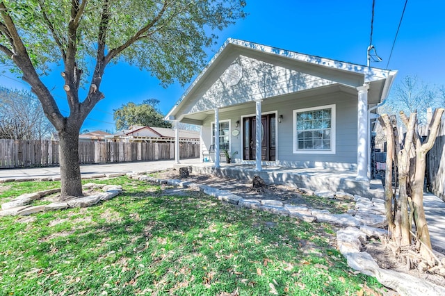 bungalow with covered porch, a patio area, fence, and a front yard