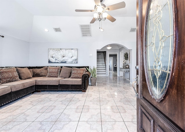 living room featuring arched walkways, lofted ceiling, and visible vents