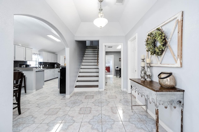 foyer entrance with lofted ceiling, arched walkways, stairway, and baseboards