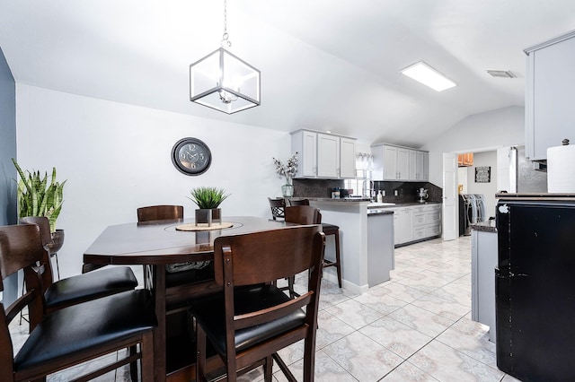 dining space with washing machine and dryer, visible vents, a notable chandelier, and lofted ceiling