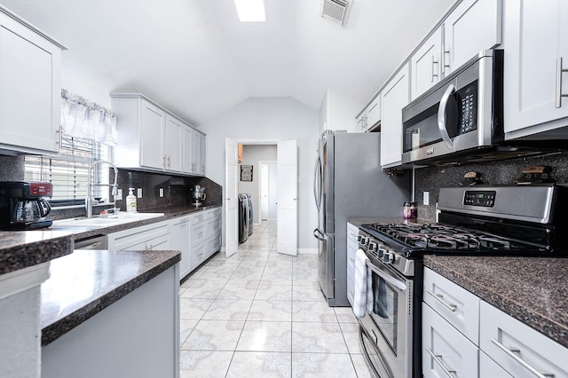 kitchen featuring stainless steel appliances, a sink, visible vents, vaulted ceiling, and tasteful backsplash