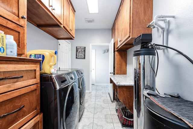 washroom featuring light tile patterned flooring, visible vents, baseboards, cabinet space, and washer and clothes dryer