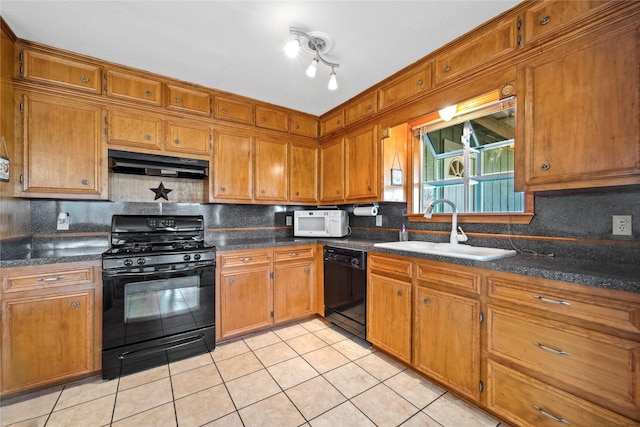 kitchen featuring under cabinet range hood, brown cabinetry, a sink, and black appliances