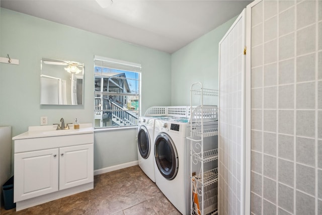 washroom with baseboards, a sink, cabinet space, and washer and dryer