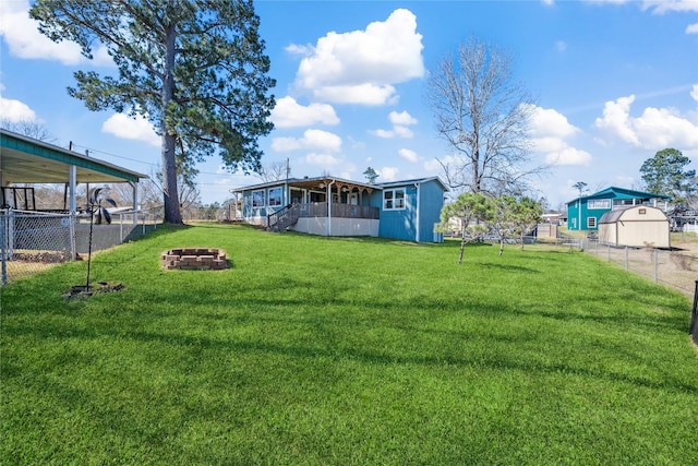 view of yard featuring a fenced backyard, an outdoor fire pit, and an outbuilding