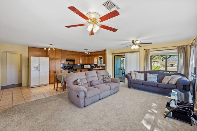 living area with light tile patterned flooring, ceiling fan, visible vents, and light carpet