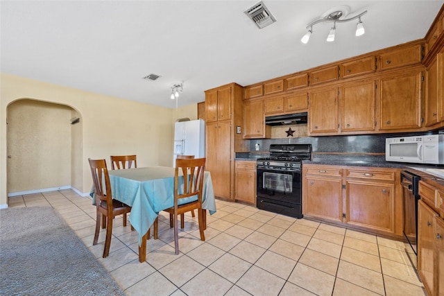 kitchen with arched walkways, light tile patterned floors, under cabinet range hood, visible vents, and black appliances