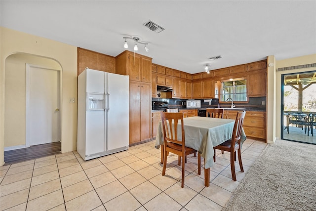 kitchen with visible vents, light tile patterned floors, a sink, under cabinet range hood, and white appliances