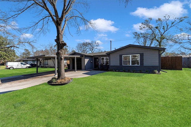 view of front facade with a carport, a front yard, concrete driveway, and fence