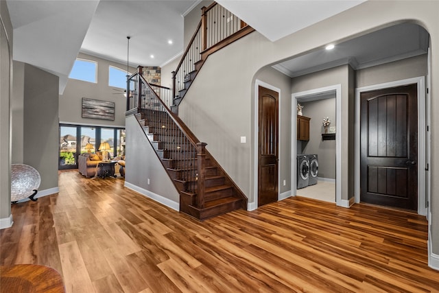 entrance foyer with light wood-style floors, stairs, arched walkways, and washer and dryer