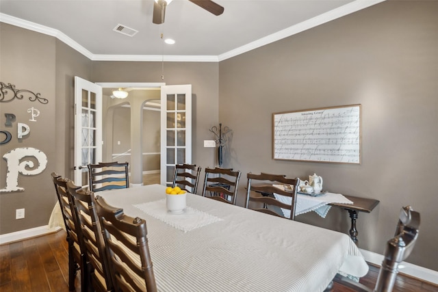 dining area featuring baseboards, crown molding, arched walkways, and wood finished floors