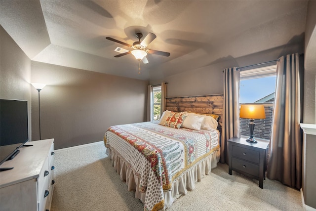 bedroom with light carpet, visible vents, and a ceiling fan