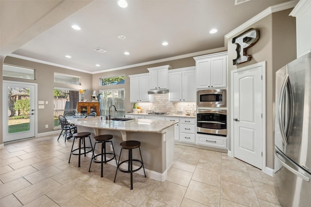 kitchen featuring decorative backsplash, stainless steel appliances, crown molding, under cabinet range hood, and a sink