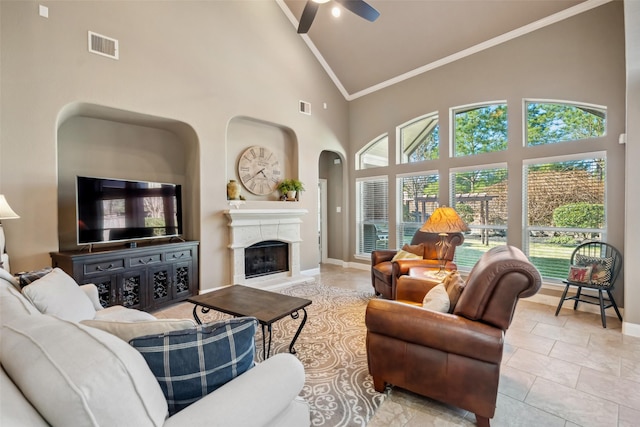 living area featuring baseboards, a wealth of natural light, visible vents, and crown molding