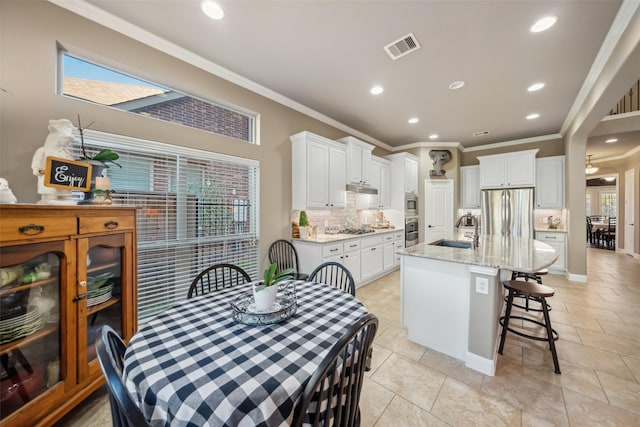 kitchen with stainless steel appliances, a sink, visible vents, a healthy amount of sunlight, and backsplash