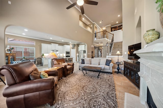 living area featuring arched walkways, recessed lighting, a high ceiling, ornamental molding, and stairs