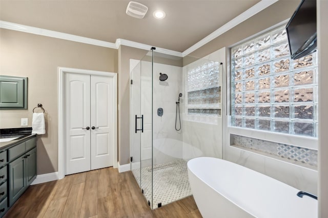 full bathroom featuring crown molding, a shower stall, vanity, wood finished floors, and a freestanding tub