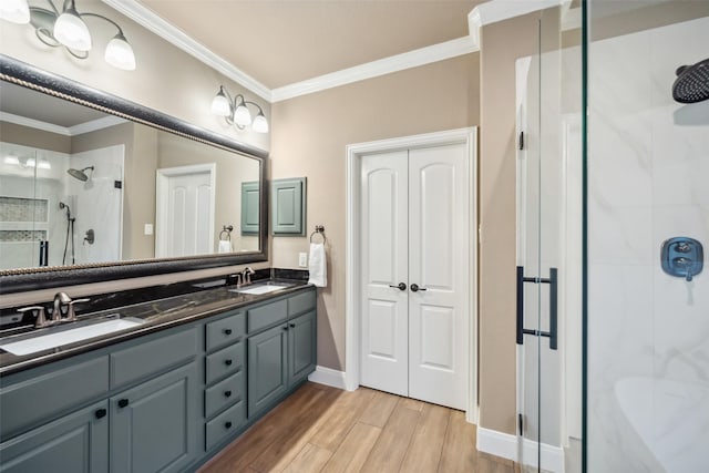 bathroom with a shower stall, ornamental molding, a sink, and wood finished floors