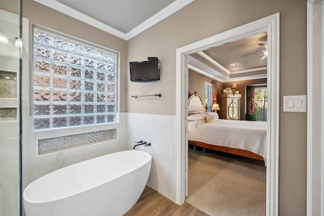 bathroom with a wainscoted wall, a freestanding bath, ornamental molding, a ceiling fan, and ensuite bath