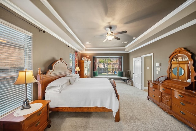 carpeted bedroom featuring a raised ceiling, crown molding, and ceiling fan