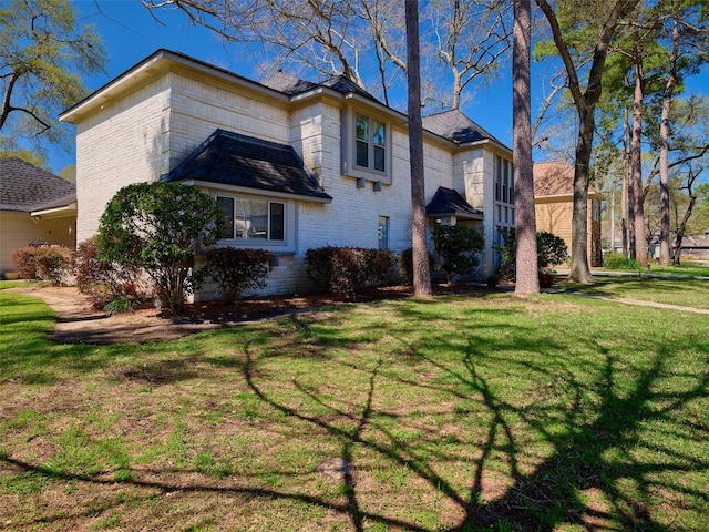 view of side of property featuring brick siding and a lawn