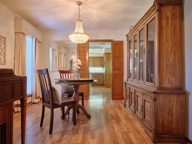 dining area featuring light wood finished floors, a chandelier, and baseboards