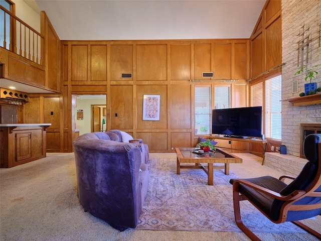 living area with light carpet, visible vents, a brick fireplace, and high vaulted ceiling