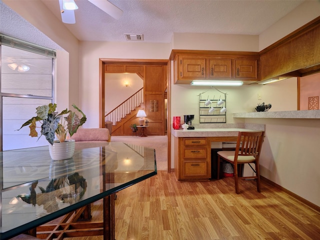 kitchen with visible vents, light wood finished floors, brown cabinetry, and light countertops