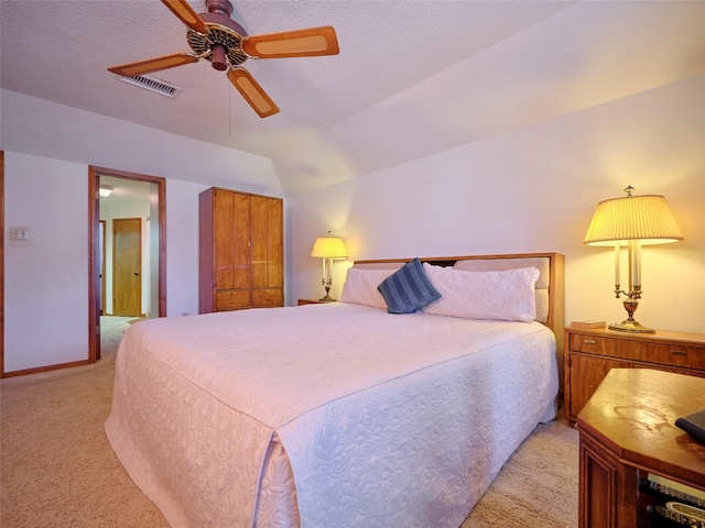 bedroom with visible vents, vaulted ceiling, light carpet, a textured ceiling, and a ceiling fan