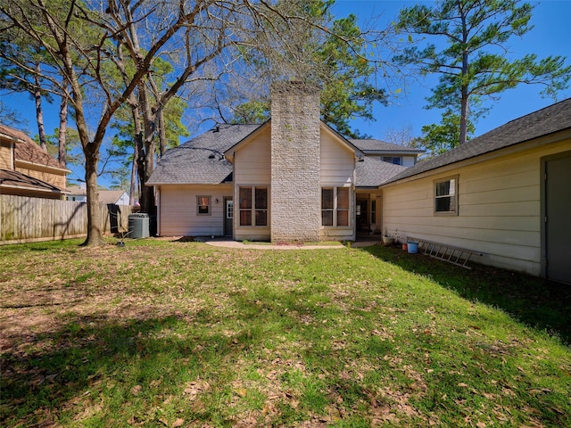 back of property featuring a yard, cooling unit, a chimney, and fence