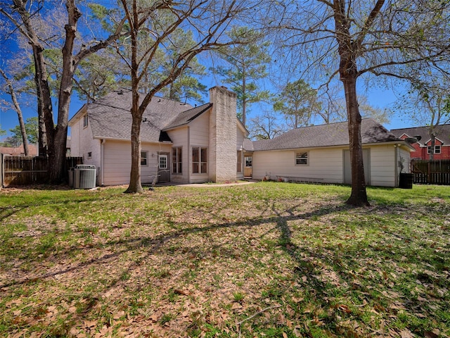 back of house featuring a yard, central AC, a chimney, and fence