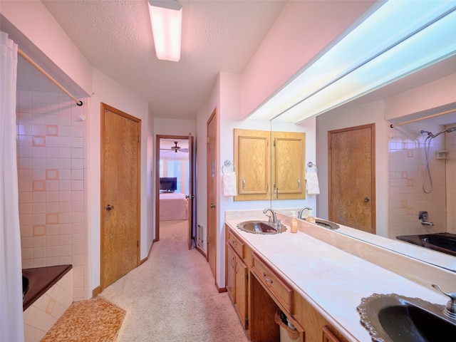 bathroom featuring double vanity, a textured ceiling, tiled shower / bath, and a sink