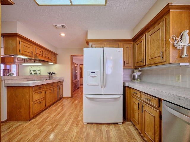 kitchen featuring white refrigerator with ice dispenser, light wood-style floors, brown cabinetry, light countertops, and dishwasher