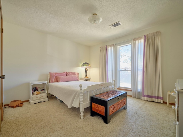 bedroom featuring carpet flooring, a textured ceiling, baseboards, and visible vents