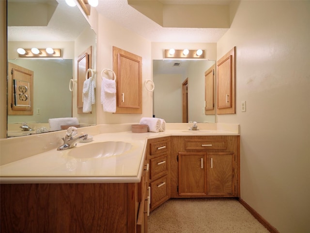 bathroom featuring a sink, baseboards, a textured ceiling, and double vanity