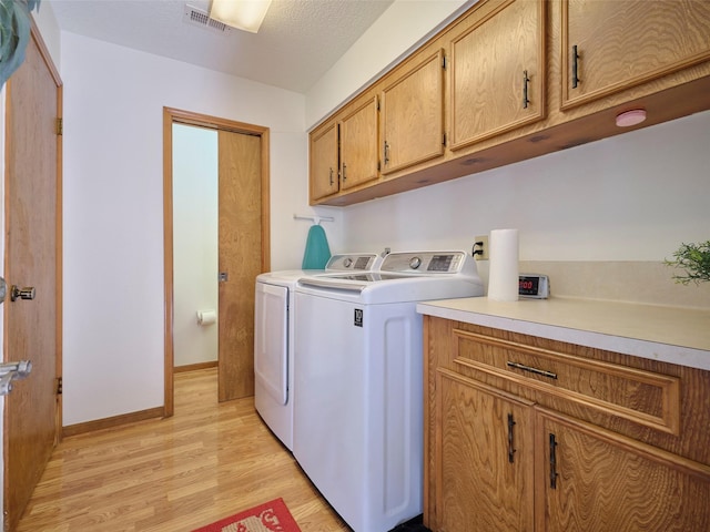 laundry room with light wood finished floors, visible vents, baseboards, washer and clothes dryer, and cabinet space