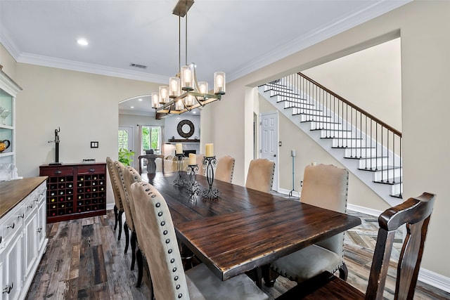 dining area with arched walkways, dark wood-style flooring, visible vents, ornamental molding, and stairs