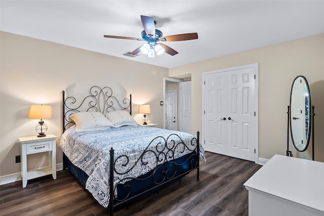 bedroom with a closet, dark wood finished floors, visible vents, and baseboards