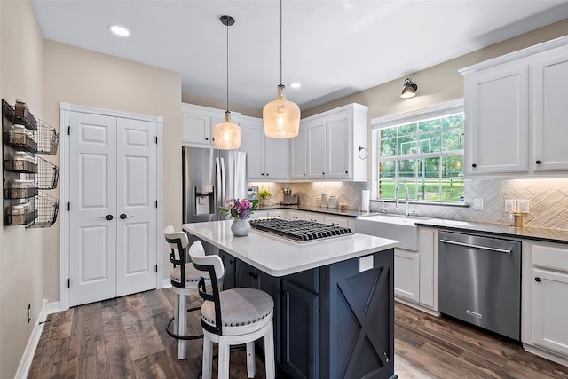 kitchen with appliances with stainless steel finishes, a sink, a center island, and white cabinets