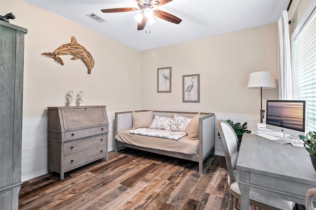 bedroom with dark wood-type flooring, wainscoting, visible vents, and a ceiling fan