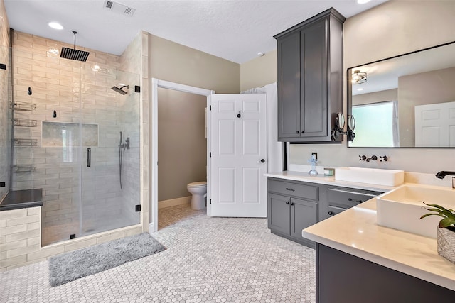 bathroom featuring toilet, vanity, visible vents, a shower stall, and tile patterned floors