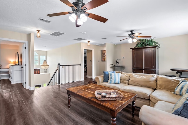 living room featuring dark wood-style flooring, visible vents, and baseboards