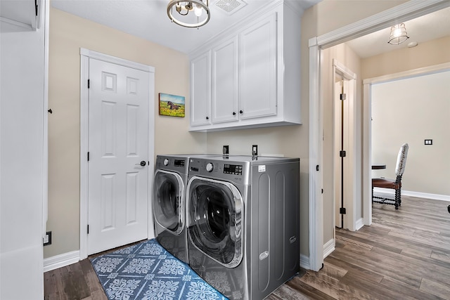 laundry area featuring dark wood-style flooring, washing machine and clothes dryer, cabinet space, visible vents, and baseboards